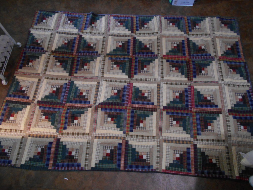 A log cabin quilt set in the Sunshine and Shadows layout, made of plaid fabrics, measuring approximately 4 1/2 x 6 feet.